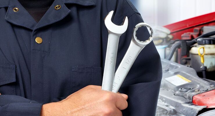 Hands of car mechanic with wrench in garage.